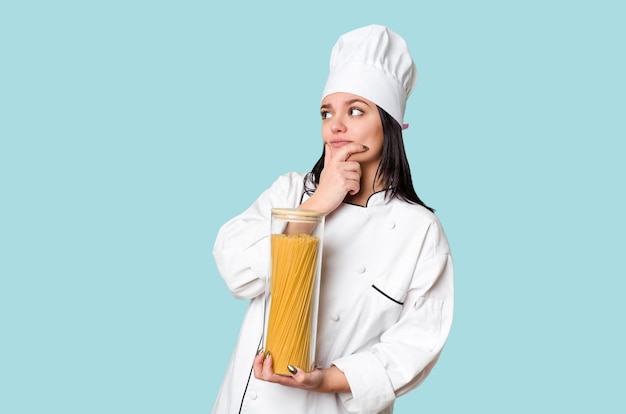 Young cook woman holding a spagetti bottle isolated