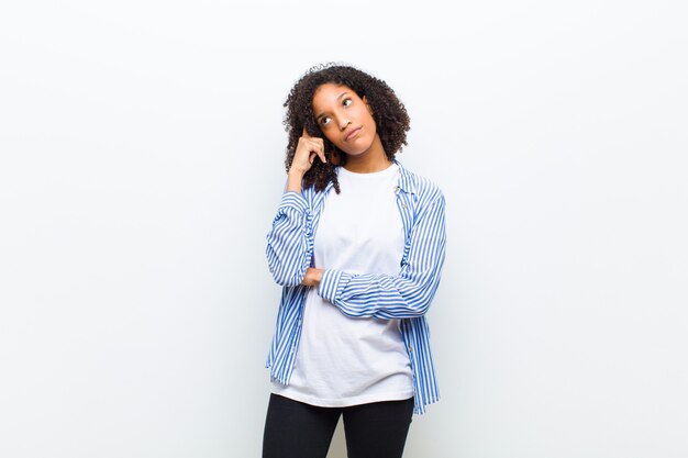 Young cool african american woman with a concentrated look, wondering with a doubtful expression, looking up and to the side