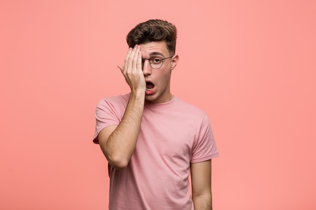 Young cool caucasian man having fun covering half of face with palm.