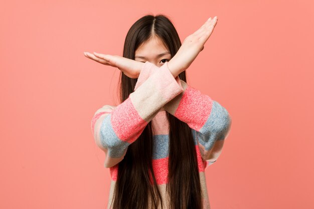 Young cool chinese woman keeping two arms crossed, denial concept.