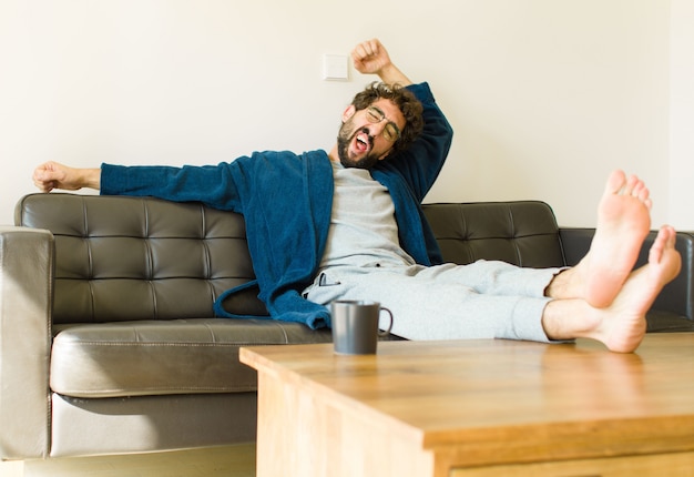 Young cool man sitting on a sofa at living room watching tv