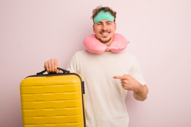 Young cool man smiling cheerfully feeling happy and pointing to the side flight passenger concept