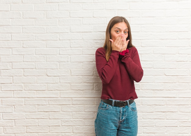 Young cool woman over a bricks wall surprised and shocked