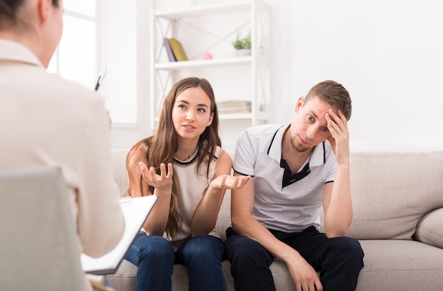 Young couple arguing on couch during therapy session. Relationship problems, family issues concept