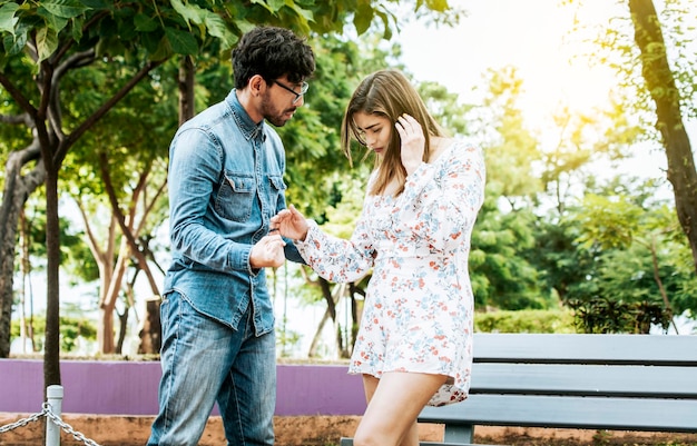 Young couple arguing misunderstanding in a park Unhappy couple standing arguing in a park Disgusted teenage couple arguing in a park Man and woman arguing in a park