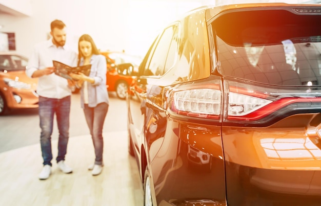 Young couple buying a new car in dealership