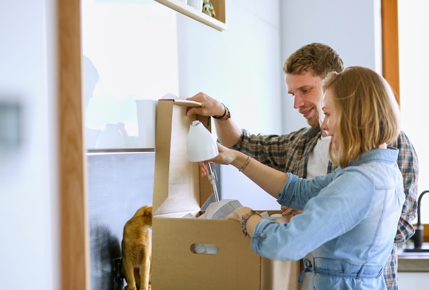 Young couple carrying big cardboard box at new homemoving house young couple