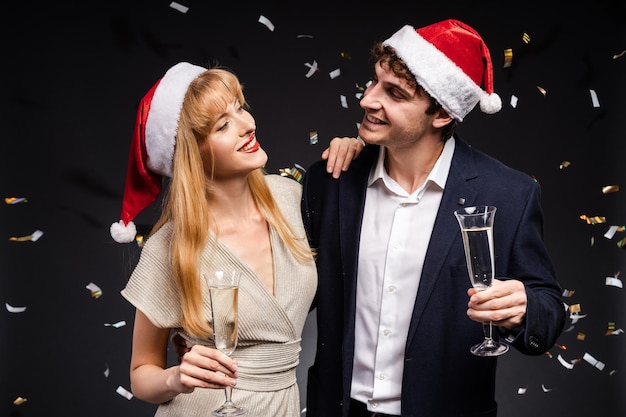 Photo young couple celebrating christmas holding champagne glasses looking at each other smiling