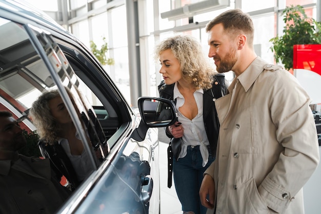 Young couple choosing their new car in a car dealership