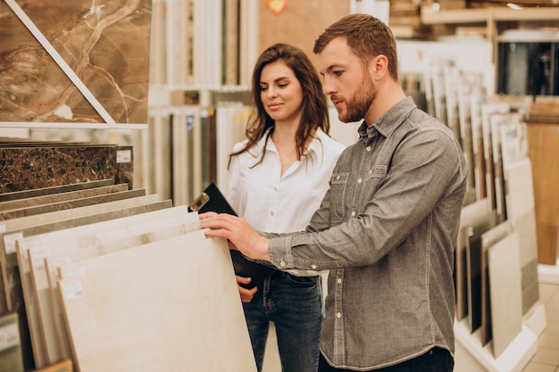 Young couple choosing tiles at building market