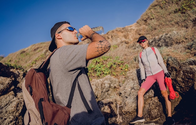 Photo young couple climbs with a rope to the top in the mountains near the ocean