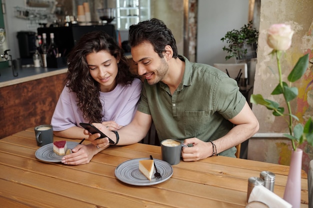 Young couple communicating in video chat in smartphone held by guy