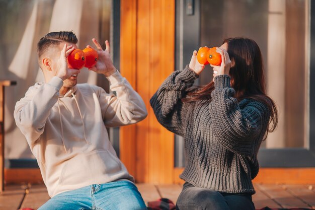 Photo young couple covered eyes with pumpkins at autumn warm day on the terrace of their house