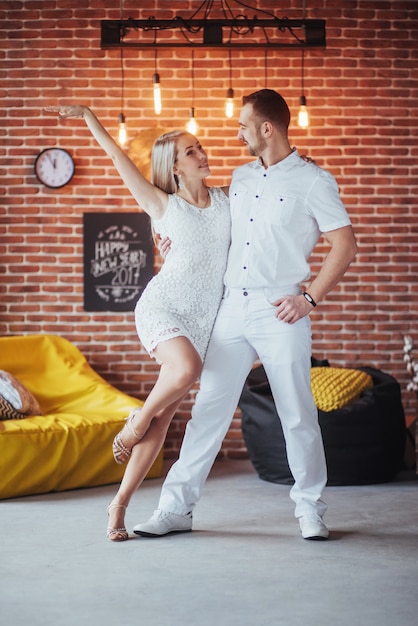 Photo young couple dancing latin music: bachata, merengue, salsa. two elegance pose on cafe with brick walls