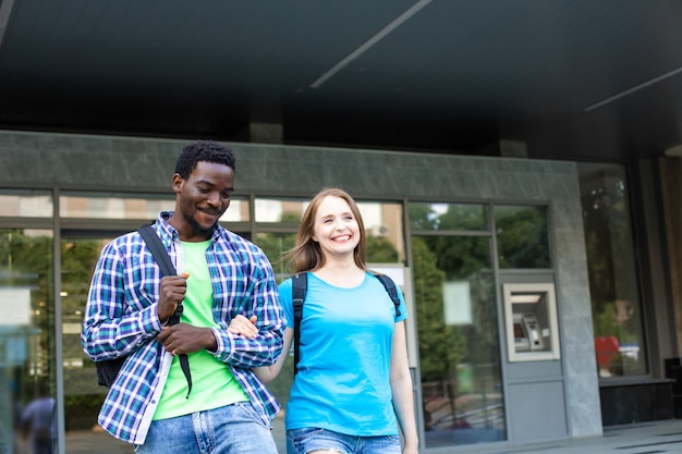 The young couple of diverse students leave the university building