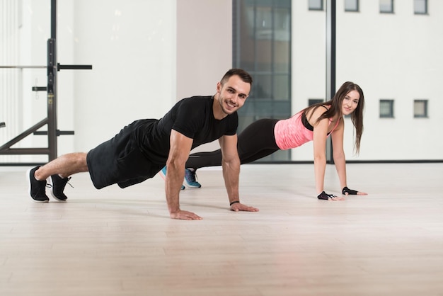 Young Couple Doing PushUp Exercise In The Gym