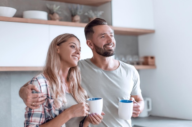 Young couple drinking coffee standing in the kitchen