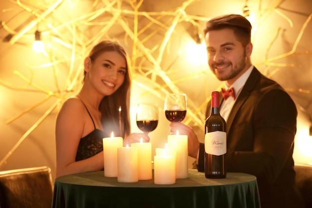 Young couple drinking wine at table with burning candles