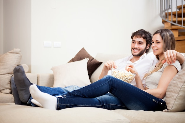 Young couple eating popcorn while watching a movie