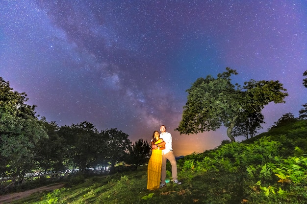 A young couple embraced looking at the beautiful Milky Way on Mount Erlaitz