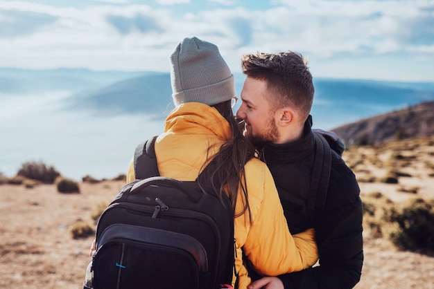 A young couple embracing standing on top of a mountain