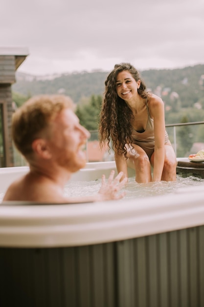 Young couple enjoying in outdoor hot tub on vacation