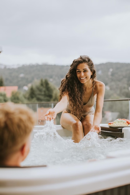 Young couple enjoying in outdoor hot tub on vacation