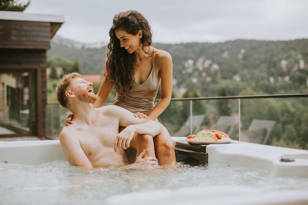 Young couple enjoying in outdoor hot tub on vacation