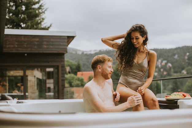 Young couple enjoying in outdoor hot tub on vacation