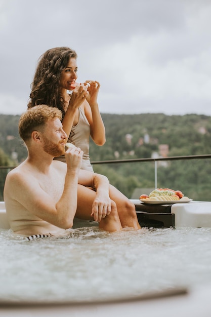 Young couple enjoying in outdoor hot tub on vacation