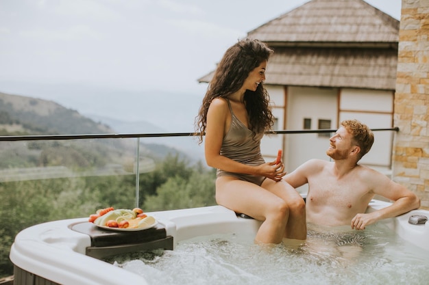 Young couple enjoying in outdoor hot tub on vacation