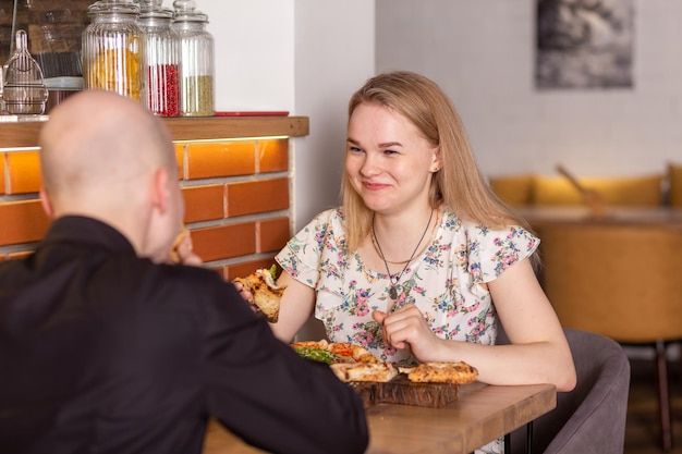 Young couple enjoying pizza while sitting in the pizzeria