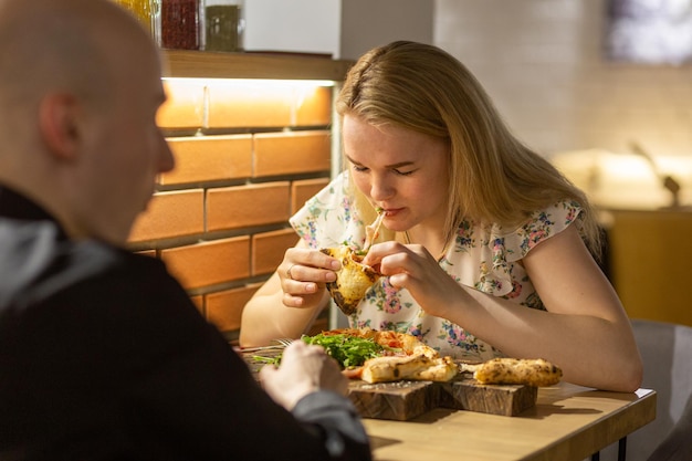 Young couple enjoying pizza while sitting in the pizzeria