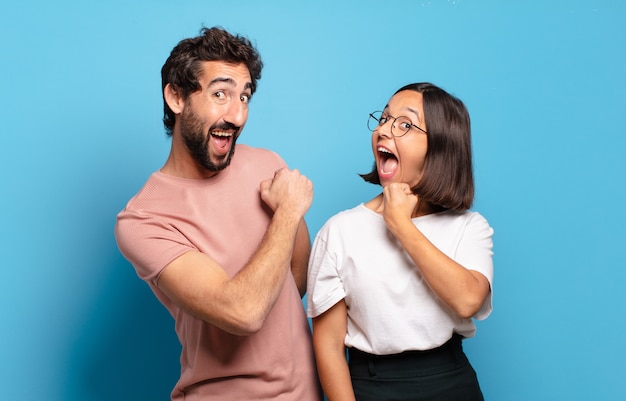 Young couple feeling happy, positive and successful, motivated when facing a challenge or celebrating good results