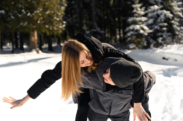 Young couple fooling around while on a winter walk near the forest a general plan of a couple in love against the backdrop of winter nature