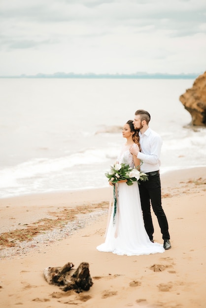 Young couple groom with the bride on a sandy beach at a wedding walk