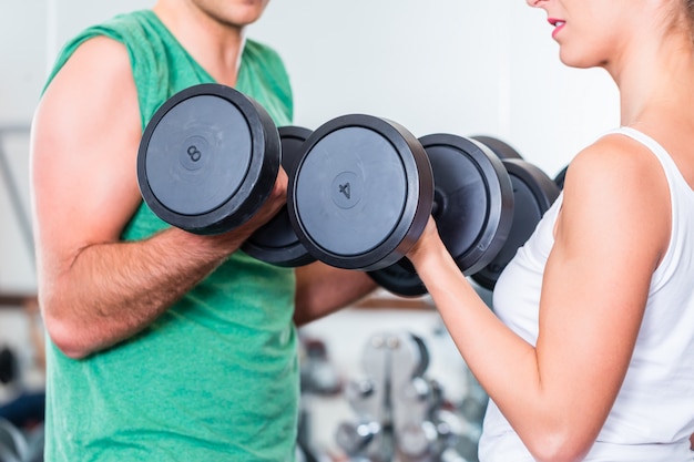 young couple in gym lifting dumbbell