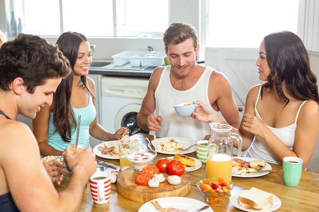 Young couple having breakfast with friends at home