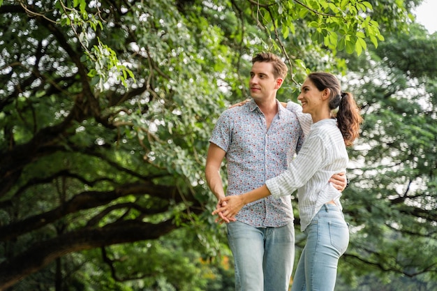 Young couple having fun in the moment of love in the park Love and tenderness Romantic man playing guitar to his girlfriend lifestyle concept