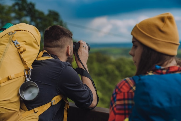 Young couple of hikers using binocular for orientation and finding the next