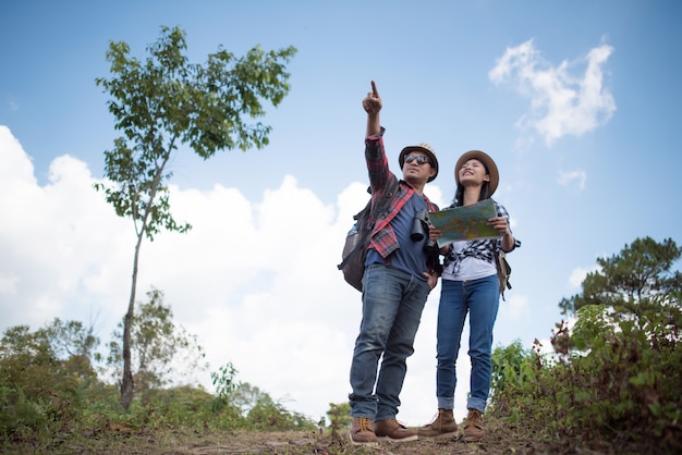 Young couple hikers with and looking on the map to find a way. 