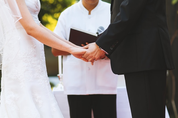 Young couple hold hand at wedding ceremony