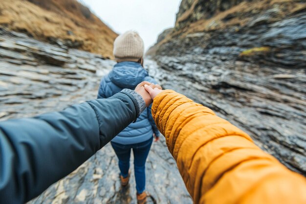 Photo young couple holding hands while hiking on rock