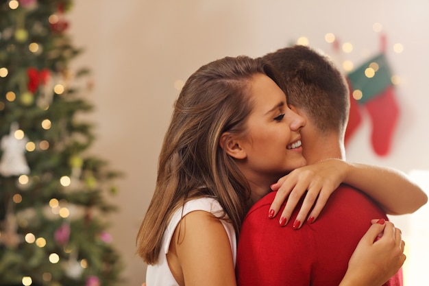 young couple hugging over Christmas tree