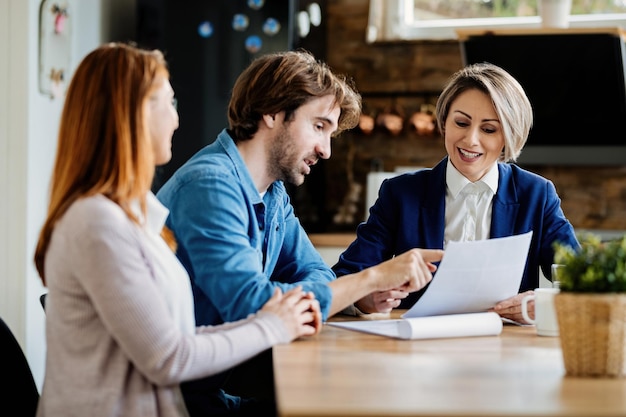 Young couple and insurance agent analyzing documents while having a meeting at their home Focus is on agent