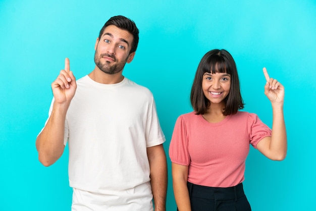 Young couple isolated on blue background showing and lifting a finger in sign of the best