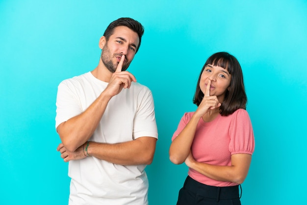 Young couple isolated on blue background showing a sign of closing mouth and silence gesture