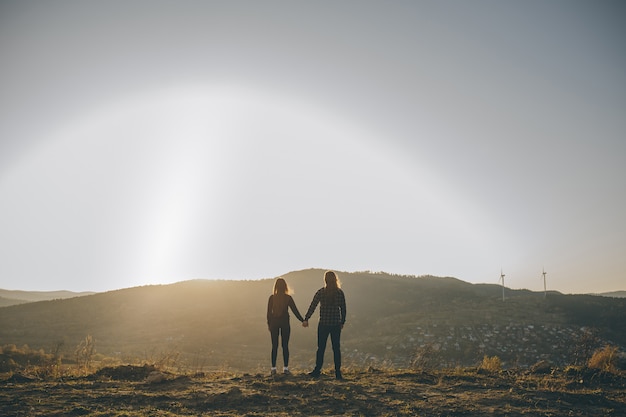 Young couple kissing on the background of a sunset in the field.