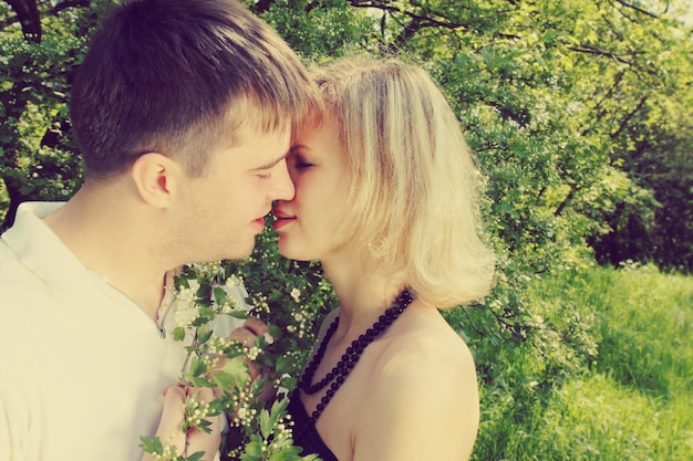 Young couple kissing near the blooming hawthorn