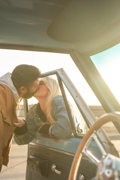 Young couple kissing through the car window